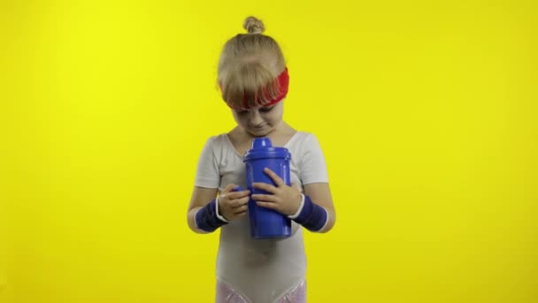Flicka i sportkläder dricksvatten för förfriskning efter fitnessövningar. Lilla atletiska barn — Stockvideo