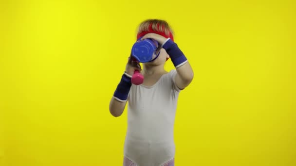 Chica en ropa deportiva haciendo ejercicios de fitness con pesas y agua potable. Pequeño niño atlético — Vídeos de Stock