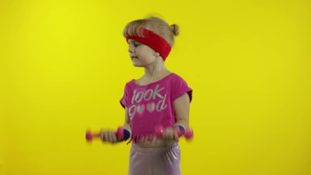 Biała dziewczyna w odzieży sportowej ćwiczy z hantlami. Ćwiczenia dla dzieci. Wysportowane dziecko — Wideo stockowe