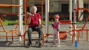 Torunum ve dedem halterlerle spor yapıyor. Kıdemli adam ve çocuklu kız