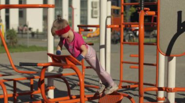 Spor kıyafetli genç bir kız çocuk parkında şınav çekiyor. Çocuklar için egzersiz. Atletik çocuk