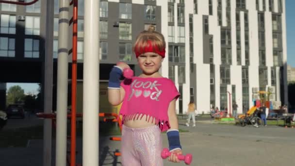 Menina caucasiana em sportswear fazendo exercícios com halteres. Treino para crianças. Criança atlética — Vídeo de Stock