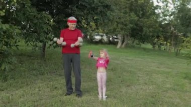 Torunum ve dedem halterlerle spor yapıyor. Kıdemli adam ve çocuklu kız