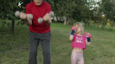 Torunum ve dedem halterlerle spor yapıyor. Kıdemli adam ve çocuklu kız