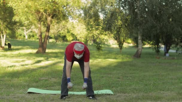 Senior grandfather making fitness exercises with dumbbells during coronavirus pandemic alone in park — Stock Video