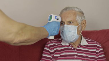 Doktorlar sıcaklığı elektronik termometreyle ölçüp hasta dedeye veriyorlar. Coronavirüs