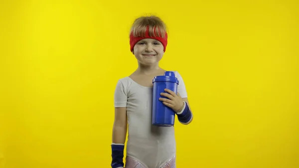 Chica en ropa deportiva de agua potable para refrescarse después de ejercicios de fitness. Pequeño niño atlético — Foto de Stock