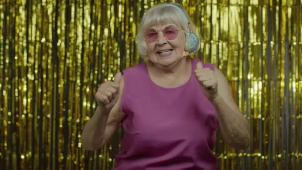 Oudere vrouw danst, luistert naar muziek op koptelefoon. Ontspannen, genieten, plezier hebben, lachen — Stockvideo