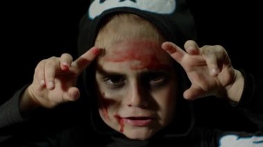 Cadılar Bayramı, yüzünde kan makyajı olan kızgın kız. Korkunç iskelet gibi giyinmiş çocuk, poz veriyor, surat yapıyor.