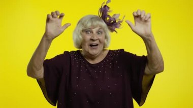 Son derece mutlu, sarı saçlı yaşlı bir kadın zaferi gülümseyerek ve başarıyla kutluyor.