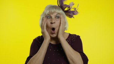 Şaşırmış yaşlı kadın şaşkınlıkla el kaldırıyor, ani zafere şaşırmış, şaşırmış görünüyor.