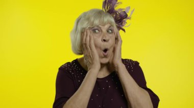 Şaşırmış yaşlı kadın şaşkınlıkla el kaldırıyor, ani zafere şaşırmış, şaşırmış görünüyor.