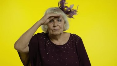 Uzağa bakan yaşlı bir kadın gözlerini dikip, uzaklarda ararken şaşkınlığını ifade ediyor.