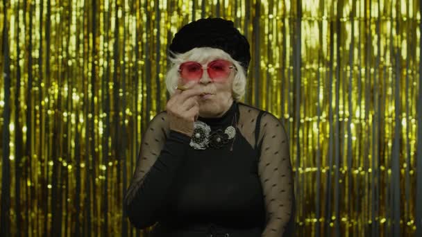 上了年纪的女人穿着时髦服装，摆设太阳镜，抽电子烟 — 图库视频影像