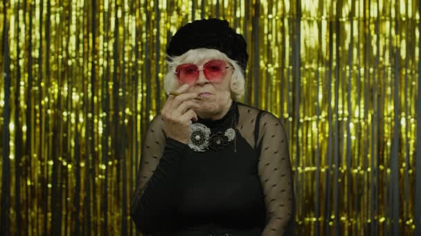Idős stílus érett nő divat ruhák napszemüvegben pózol, füst elektronikus cigaretta — Stock videók