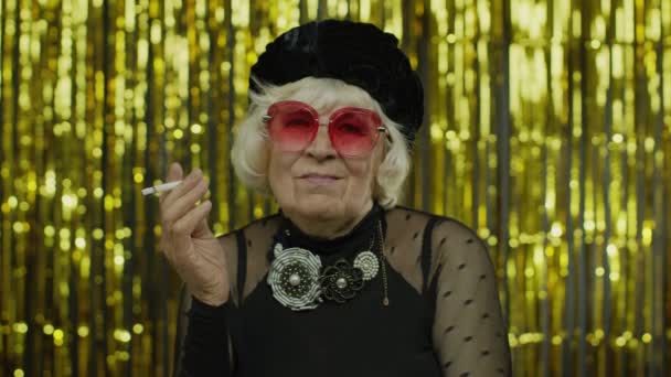 Anziani stile maturo donna d'affari di moda vestiti neri in posa occhiali da sole, fumo sigaretta — Video Stock