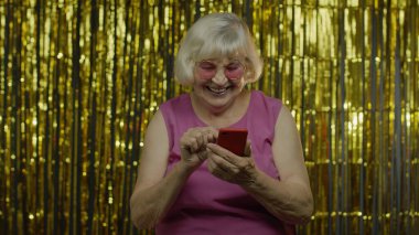 Son sınıf mutlu yaşlı kadın cep telefonunda mesaj yazıyor, internette sohbet ediyor, sosyal ağ kuruyor