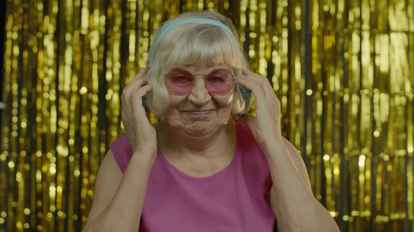Anciana mayor baila, escucha música en los auriculares. Relajarse, disfrutar, divertirse, sonreír — Foto de Stock