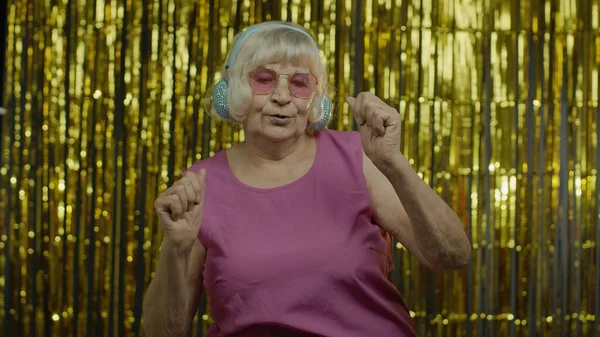 Anciana mayor baila, escucha música en los auriculares. Relajarse, disfrutar, divertirse, sonreír —  Fotos de Stock