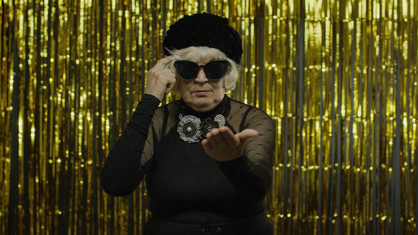 Недовольна, что пожилая женщина демонстрирует глупые жесты. Пожилая бабушка на желтом фоне