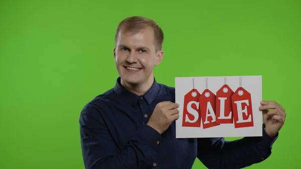 Geweldige kortingen. Happy vrolijke blonde man in blauw shirt tonen Sale woord advertentie inscriptie — Stockfoto