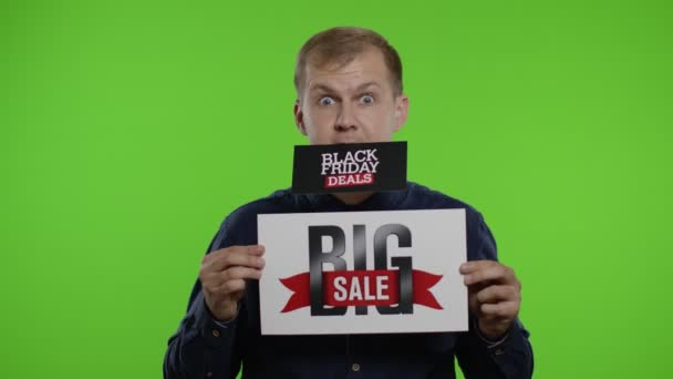 Man shopper holding Black Friday Deals advertentie in zijn maand en tonen Big Sale inscriptie — Stockvideo