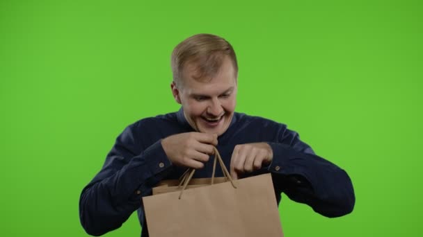 Fröhlicher Mann zeigt Black-Friday-Aufschrift aus Einkaufstüten und lächelt zufrieden über niedrige Preise — Stockvideo