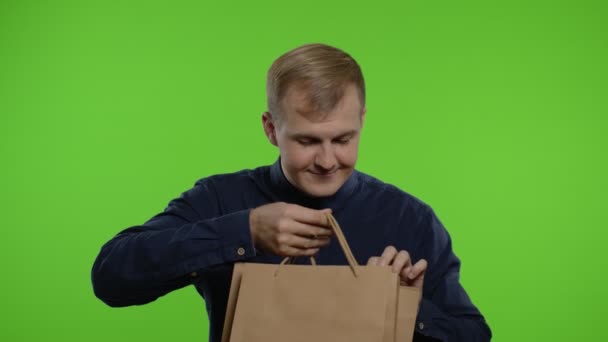 Hombre sacando descuentos de venta inscripción de bolsas de compras, sonriendo satisfecho con los precios bajos — Vídeos de Stock