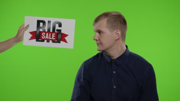 Napis Big Sale pojawia się obok uśmiechniętego mężczyzny. Facet świętuje, pokazuje kciuki do góry. Czarny piątek — Wideo stockowe