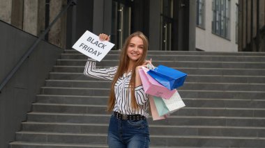 Neşeli kız Kara Cuma yazılı mesaj ilanı gösteriyor. Düşük fiyatlı online alışveriş