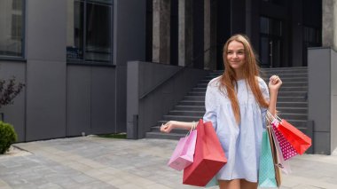 Alışveriş merkezinden alışveriş torbalarıyla gelen bir kız. İndirim kavramı, Kara Cuma 'da düşük fiyatlar