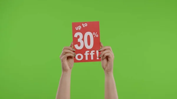 Hasta 30 por ciento de descuento en la inscripción de publicidad en la hoja de papel en las manos de las mujeres en la clave de croma — Foto de Stock