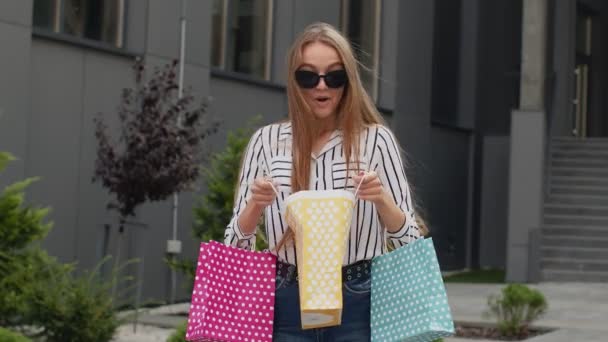 Renkli alışveriş çantaları tutan kız, moda mağazasında indirimler, alışveriş merkezlerinde alışveriş yapan kız. — Stok video