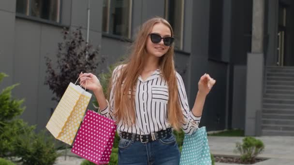Стильна дівчина з сумками для покупок, радісні знижки в магазині, махаючи руками, вітаю, вітаю — стокове відео