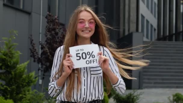 Teen girl showing Up To 50 percent Off inscription, advertising discounts, shopping on Black Friday — Stock Video