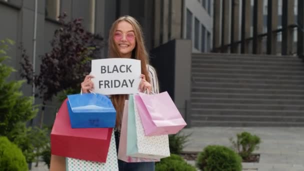 Joyful menina adolescente mostrando Black Friday inscrição, sorrindo, olhando satisfeito com preços baixos Filmagem De Bancos De Imagens Sem Royalties