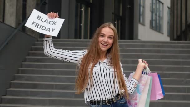Χαρούμενο κορίτσι που δείχνει τη διαφήμιση κειμένου της Μαύρης Παρασκευής. Online αγορές με χαμηλές τιμές — Αρχείο Βίντεο