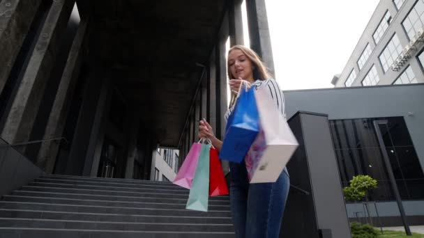 Menina andando com sacos de compras, olhando satisfeito com a compra, desfrutando de descontos na Black Friday — Vídeo de Stock