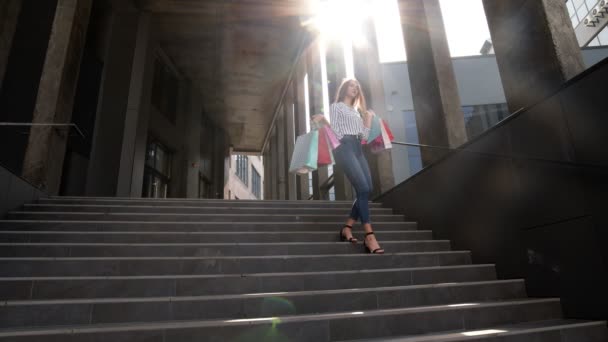 Lächelndes Mädchen läuft mit Einkaufstüten aus dem Einkaufszentrum und freut sich über den Einkauf am Black Friday — Stockvideo
