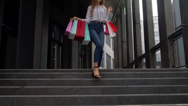 Fille souriante marchant du centre commercial avec des sacs à provisions, heureux avec des prix bas sur Black Friday — Video