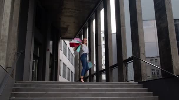 Девушка с сумками, шипение, танцы, глядя удовлетворены покупкой, наслаждаясь ценами скидки — стоковое видео