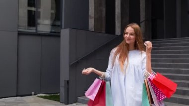Alışveriş merkezinden alışveriş torbalarıyla gelen bir kız. İndirim kavramı, Kara Cuma 'da düşük fiyatlar