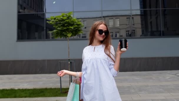 Les filles restent près du centre commercial avec des sacs à provisions et boire du café. Satisfait et satisfait de l'achat — Video