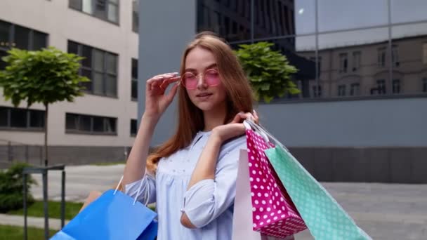 Chica sosteniendo coloridas bolsas de compras, regocijo descuentos en la tienda de moda, disfrutar de las compras en el centro comercial — Vídeos de Stock