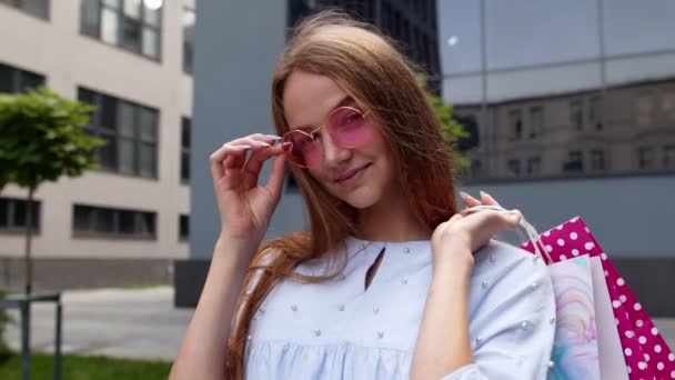 3.年轻女子戴着粉色太阳镜，站在购物中心门口，提着购物袋 — 图库视频影像