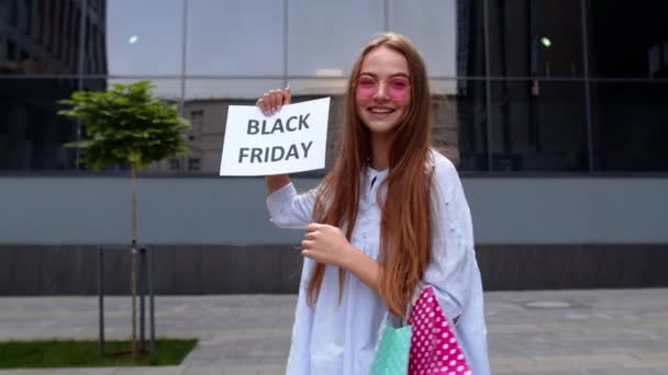 Chica alegre mostrando el anuncio de texto de inscripción de Viernes Negro. Compras en línea con precios bajos — Vídeos de Stock