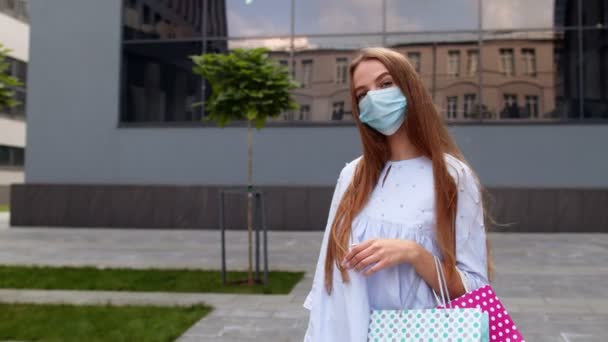 Nastolatka z wielobarwnymi torbami na zakupy w masce ochronnej. Czarny Piątek podczas koronawirusu — Wideo stockowe