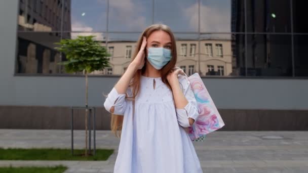 Menina adolescente com sacos de compras multicoloridos usando máscara de proteção. Black Friday durante coronavírus — Vídeo de Stock