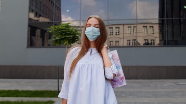 Tinédzser lány többszínű bevásárlószatyorral, védőmaszkot visel. Fekete péntek a koronavírus alatt — Stock videók