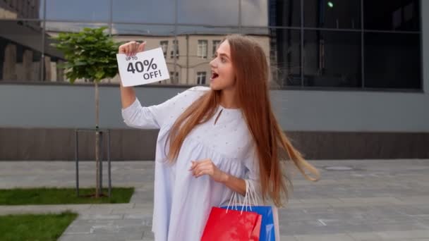 Chica alegre que muestra hasta 40 por ciento de descuento en el anuncio de texto. Compras en línea con precios bajos — Vídeos de Stock